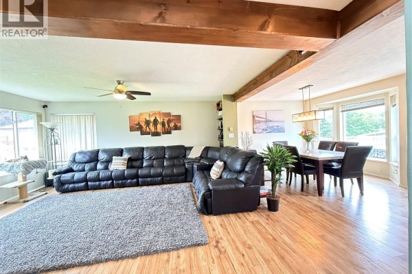 Living and dining area with black leather sectional, wood dining table, and wood floors. - 2116 Northland Rd, Port Mcneill