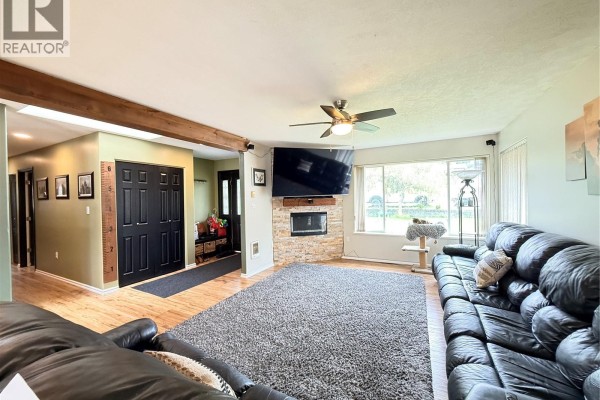 View of the living room, fireplace, black sectional, and entrance hallway. - 2116 Northland Rd, Port Mcneill