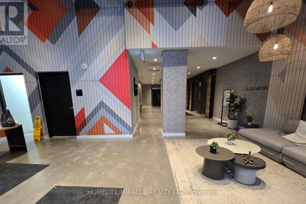 A wide view of an apartment building lobby with elevators, seating area, and geometric wall art. - 2118 - 10 Abeja Street, Vaughan