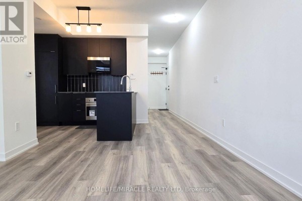 A modern kitchen with black cabinetry, a dark island, and light wood-look flooring. - 2118 - 10 Abeja Street, Vaughan