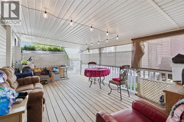 View of a covered deck with light-colored wood flooring, seating, and string lights. - 2118 Buttle Lake Way, Nanaimo