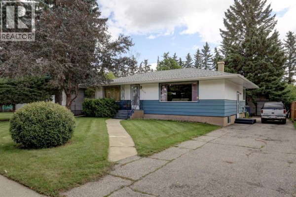 Side exterior view of the residential property, showing the driveway and side yard. - 2119 Halifax Crescent Nw, Calgary