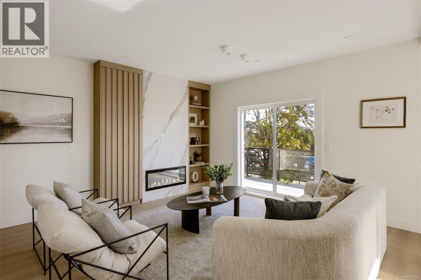 Living area with modern furniture, a fireplace, built-in shelving, and a sliding glass door overlooking trees. - 2119 Kingbird Dr, Langford