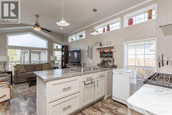 Bedroom with a queen-size bed, patterned bedding, nightstands, and windows. - 212, 10046 Township Road 422, Rural Ponoka County