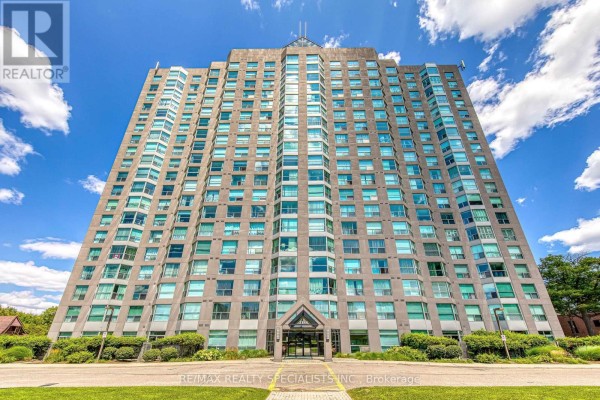 Low-angle view of a tall, light-grey apartment building facade with many windows against a blue sky. - 212 - 2155 Burnhamthorpe Road W, Mississauga