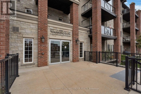 Entrance to The Washington apartment building with double glass doors and stone facade. - 212 - 5 Greenwich Street, Barrie