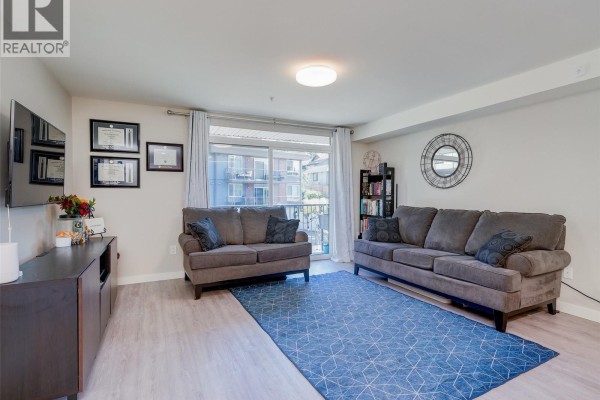Living room with two sofas, a blue geometric rug, and a sliding glass door. - 212 110 Presley Pl, View Royal