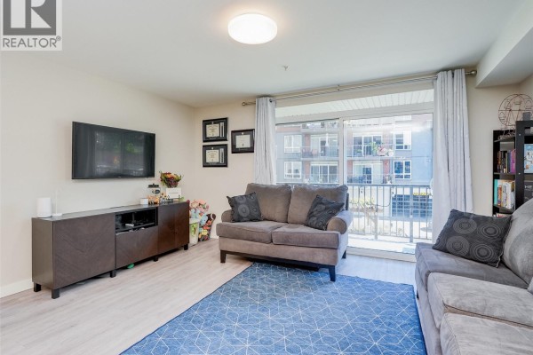Living room with sofas, a blue rug, and a large sliding glass door overlooking balconies. - 212 110 Presley Pl, View Royal