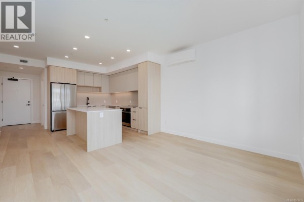 Kitchen with light wood cabinets, white quartz island, stainless steel refrigerator, and beige backsplash. - 212 3564 A Ryder Hesjedal Way, Colwood