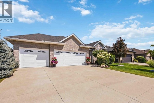 Side exterior view of a single-family home showing the triple-car garage and manicured lawn. - 212 Basquiat Crescent, Sarnia