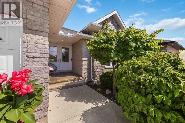 Close-up view of the home's entrance with stone siding, double doors, and green shrubbery. - 212 Basquiat Crescent, Sarnia