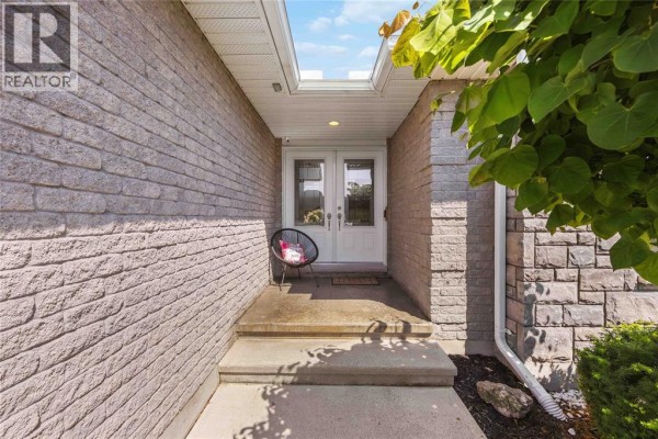 Pathway leading to the front entrance featuring stone siding, double glass doors, and a decorative chair. - 212 Basquiat Crescent, Sarnia