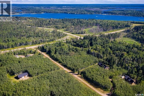 Aerial view of wooded lots with scattered houses and a distant blue lake. - 212 Deer Ridge Drive, Emma Lake