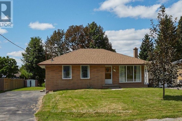Exterior view of a brick bungalow with a lawn, driveway, and trees. - 212 Hallett Avenue, Whitby