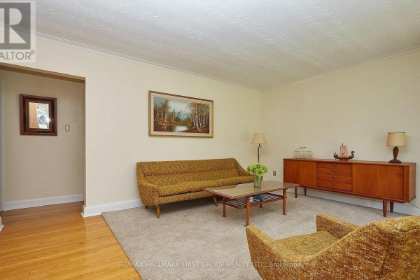 Living room with a sofa, armchair, credenza, and artwork on the wall. - 212 Hallett Avenue, Whitby