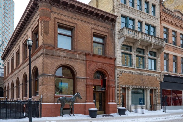 Exterior of a historic red brick building with arched windows and a horse statue. - 212 Mcdermot, Winnipeg