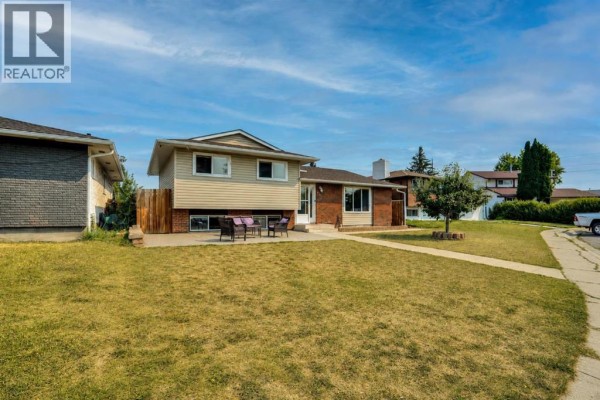 Wide angle view of the front and side of a residential house with a large lawn. - 212 Pinetree Place Ne, Calgary