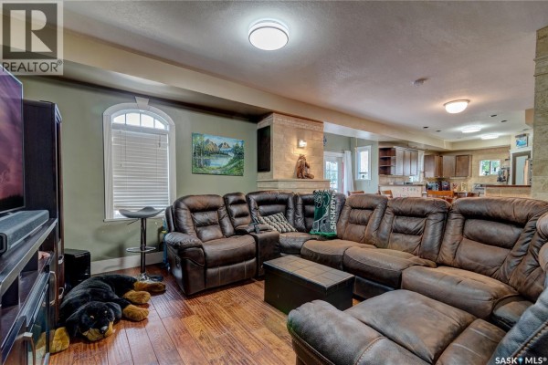 Living room with a large brown leather sectional sofa, stone accent wall, and hardwood floors. - 212 Prospect Street, Belle Plaine