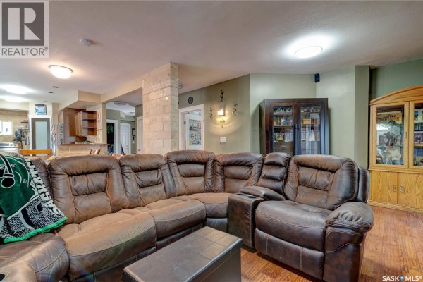 Another view of the living room showing the large brown leather sectional, a wooden cabinet, and green walls. - 212 Prospect Street, Belle Plaine