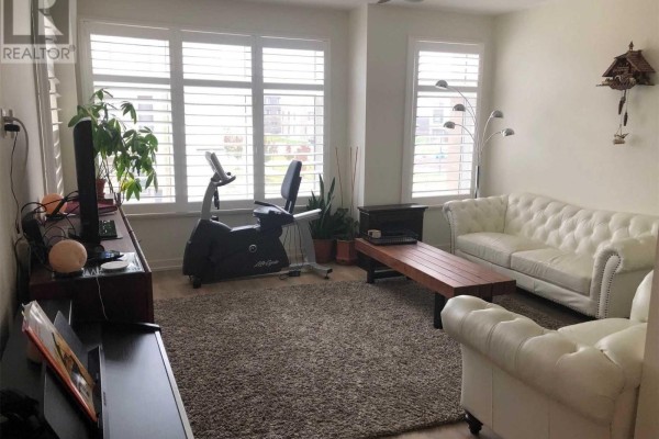 Living room with white tufted sofas, a stationary bike, a TV, and white plantation shutters covering the windows. - 212 Squire Crescent, Oakville