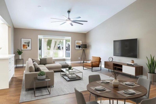 Living and dining area with a sectional sofa, accent chair, TV, and round dining table. - 212 Wilmot Trail, Clarington