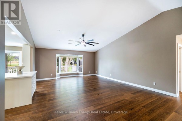 Spacious living area with vaulted ceiling, hardwood floors, and a large bay window. - 212 Wilmot Trail, Clarington