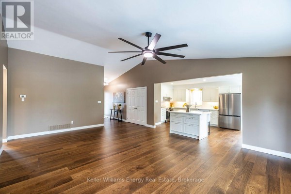 Open concept living space with hardwood floors, vaulted ceiling, and view of the kitchen. - 212 Wilmot Trail, Clarington