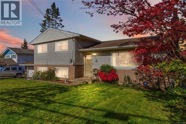Exterior of the house at dusk with a red maple tree and lawn. - 2123 Church Rd, Sooke
