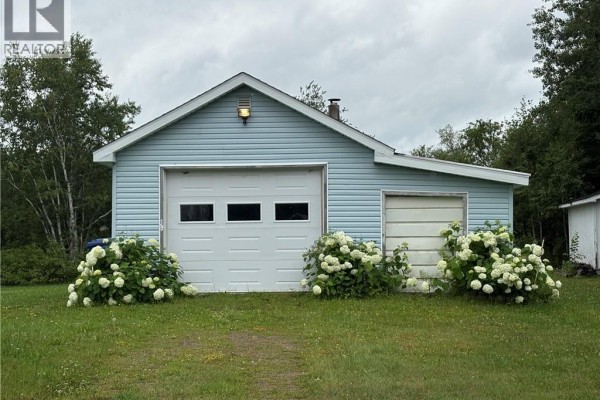 Light blue detached garage with two large white doors and white hydrangeas in front. - 2123 Sainte-louise, Sainte Louise