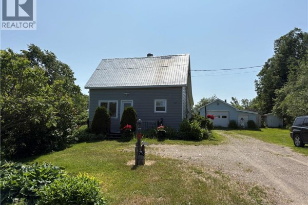 View of the grey house and detached garage from the driveway. Green trees and shrubs. - 2123 Sainte-louise, Sainte Louise