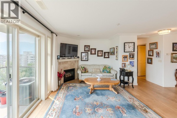Living room with sliding glass doors, fireplace, sofa, and wood flooring. - 2125 Atkinson Street Unit# 901, Penticton