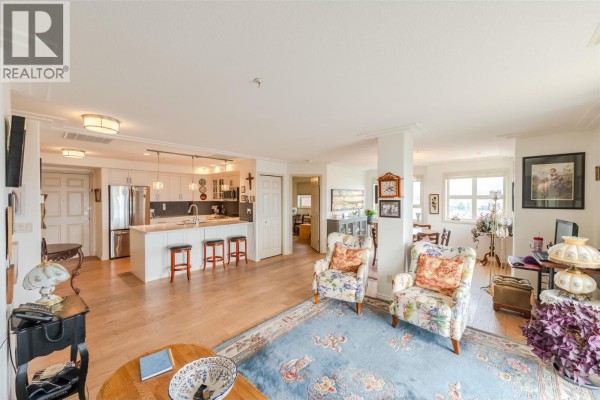 Open-concept living area showing kitchen, island, dining space, and fireplace. - 2125 Atkinson Street Unit# 901, Penticton