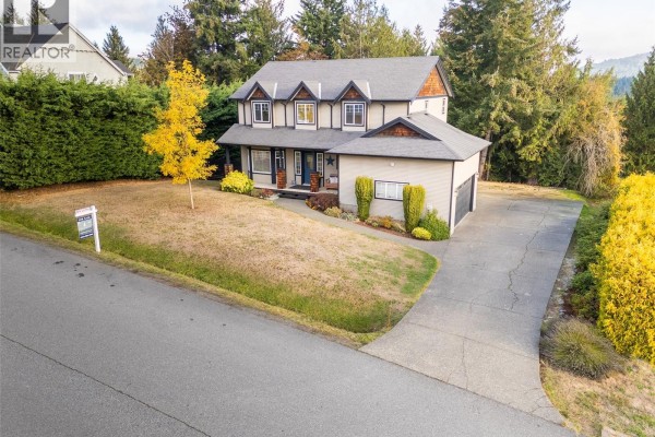Front view of the beige two-story house with a driveway and attached garage. - 2125 Wildflower Rd, Shawnigan Lake