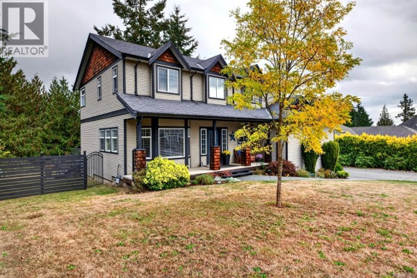 Side exterior view of the house showing the porch, landscaping, and lawn. - 2125 Wildflower Rd, Shawnigan Lake
