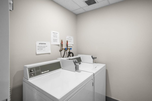 Laundry room with two white washing machines and a clothes dryer. - 212c 160 Esplanade Avenue, Harrison Hot Springs, Harrison Hot Springs