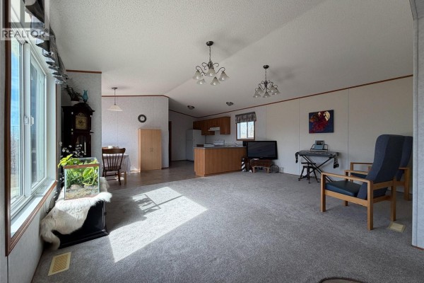 A wide view of the open living room, kitchen, and dining area of a mobile home. - 213 - 217 2nd Street W, Climax
