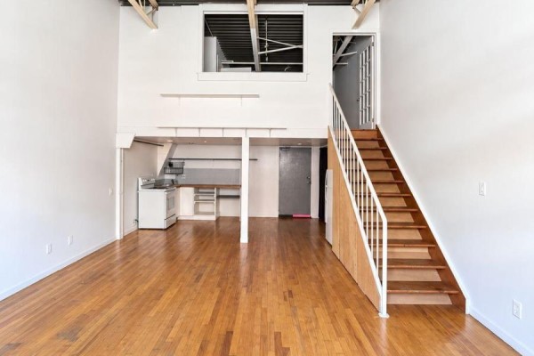 Loft-style apartment interior with open space, hardwood floors, a staircase, and a small kitchen area. - 213 - 227 Sterling Road E, Toronto