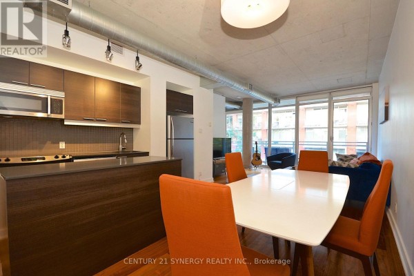 Open concept living area with a kitchen island, dining table, and seating area. - 213 - 354 Gladstone Avenue, Ottawa