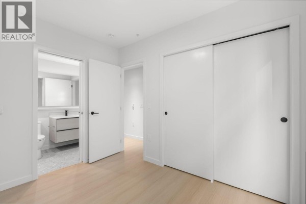 Bedroom with sliding closet doors, white walls, and entrance to bathroom. - 213 2015 St. Johns Street, Port Moody