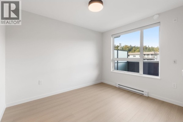 Empty room with large window overlooking buildings and trees. - 213 2015 St. Johns Street, Port Moody