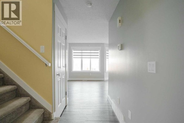 Hallway interior showing a console table, stairs, and a closed door on the right. - 213 Parry Crescent, Fort Mcmurray