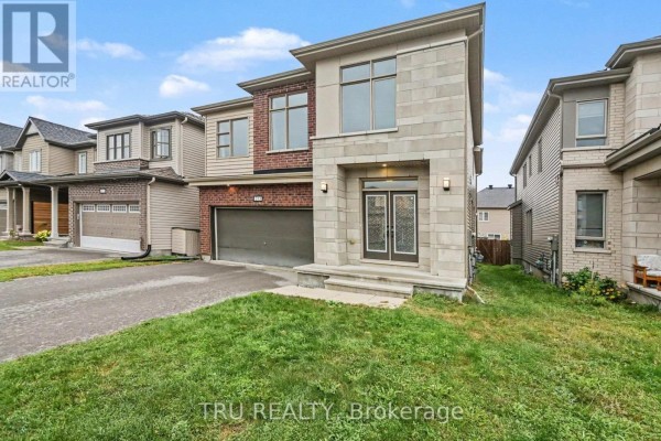 Side view of the modern two-story house with brick and stone exterior, manicured lawn, and driveway. - 213 Quarter Horse Street, Ottawa