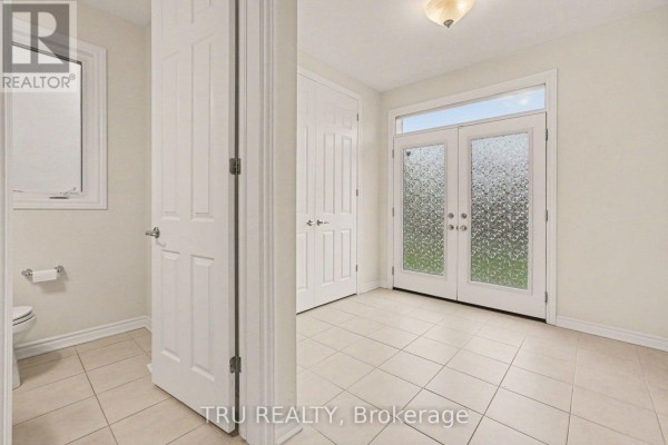 Interior entryway with tiled floor, white walls, a closet, a toilet, and double glass doors leading outside. - 213 Quarter Horse Street, Ottawa