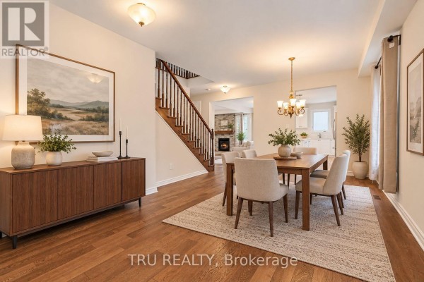 Dining room featuring a wooden table with chairs on a rug, a credenza, hardwood floors, and a view to the kitchen. - 213 Quarter Horse Street, Ottawa