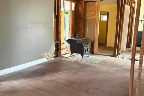 View of wooden stairs with white risers and dark treads next to an unfinished room and a kitchen counter. - 213 Second Avenue, Alexander