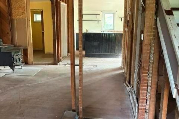 Black paneled bar with a wooden countertop in a room with light-colored walls and windows. - 213 Second Avenue, Alexander