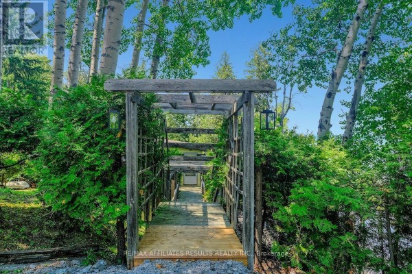 Wooden pergola and walkway leading through lush green trees towards the water. - 2130 B River Road, Mcnab/braeside
