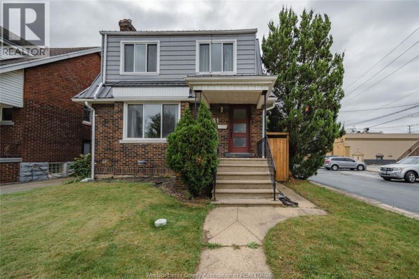 Front view of the house showing the brick facade, grey siding, and covered porch. - 2131 Lincoln Road, Windsor