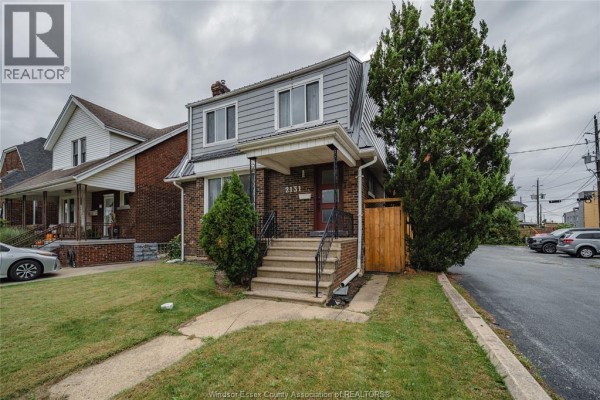 Front yard and entryway of the house with a paved driveway and lush green lawn. - 2131 Lincoln Road, Windsor
