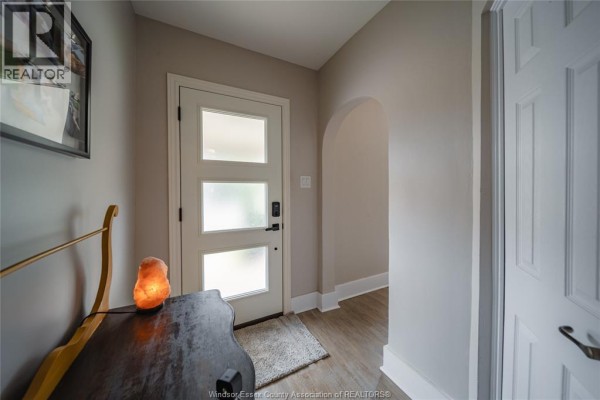 Interior entryway with a white door, arched doorway, and a wooden console table. - 2131 Lincoln Road, Windsor